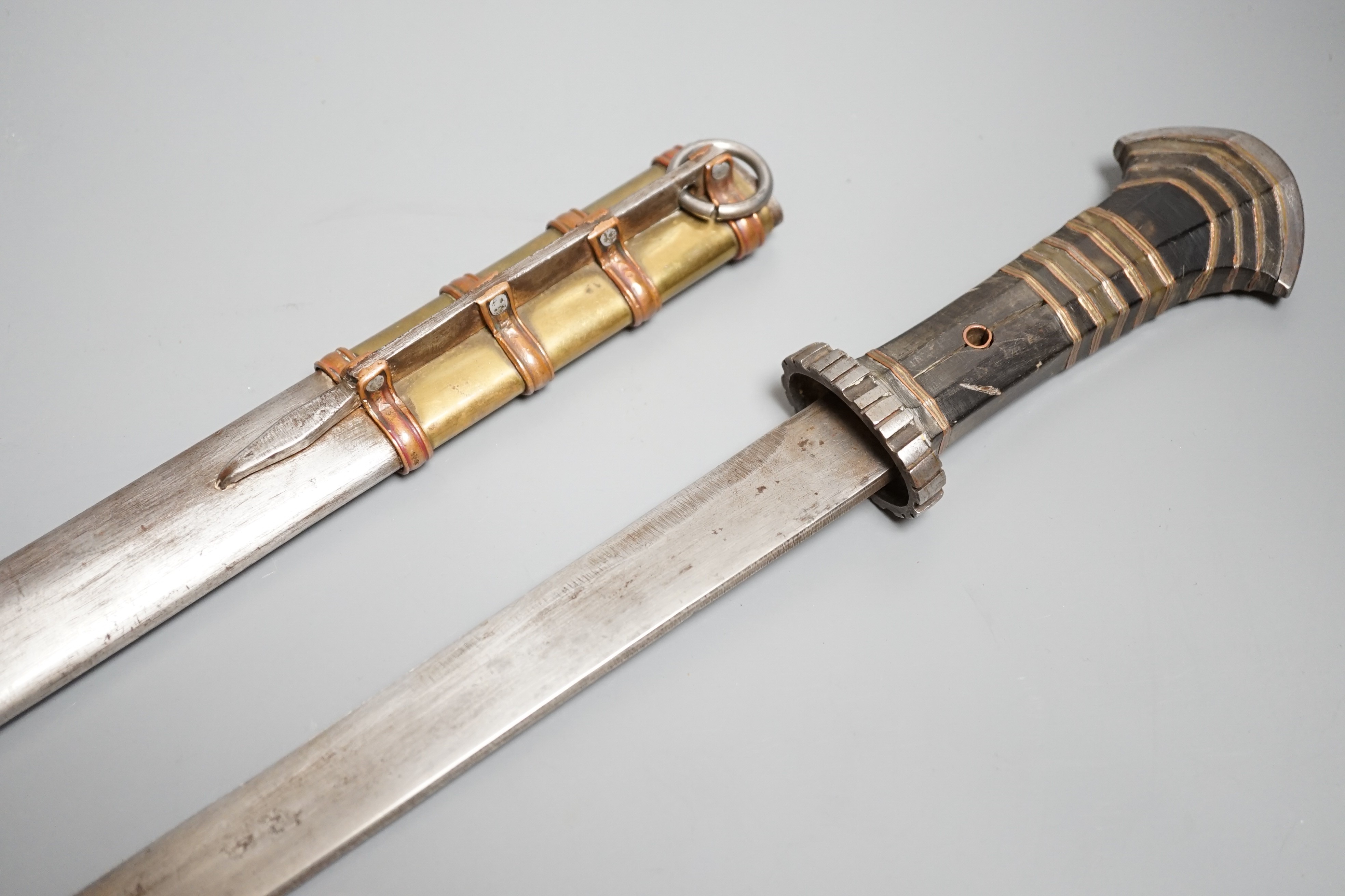 A large Tibetan dagger, early 20th century, horn handle with layers of copper and brass, iron pommel, guard and sheath with copper and brass mounts, length 46cms